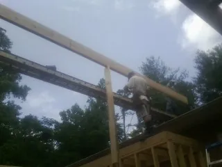 Carpenter setting a ridge beam over a new addition frame — Ice Dam Removal by Roofing Brothers in Mcadoo