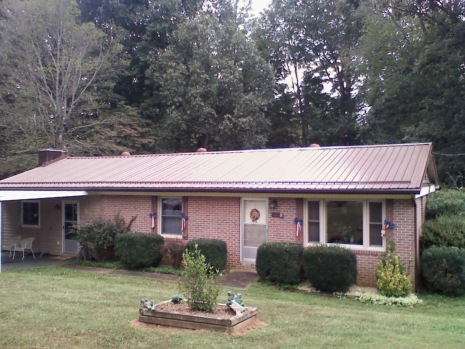Bronze metal roof on a brick ranch home with a carport in Mcadoo