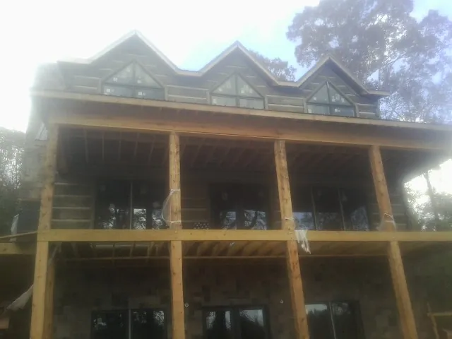 Dormers and porch framing on a large log home under construction — Roof Coating work by our crew in Mcadoo
