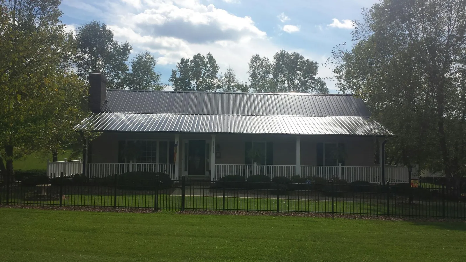 Gray metal roof on a brick ranch with a full width front porch — Gutter Guard Installation work by our crew in Mcadoo
