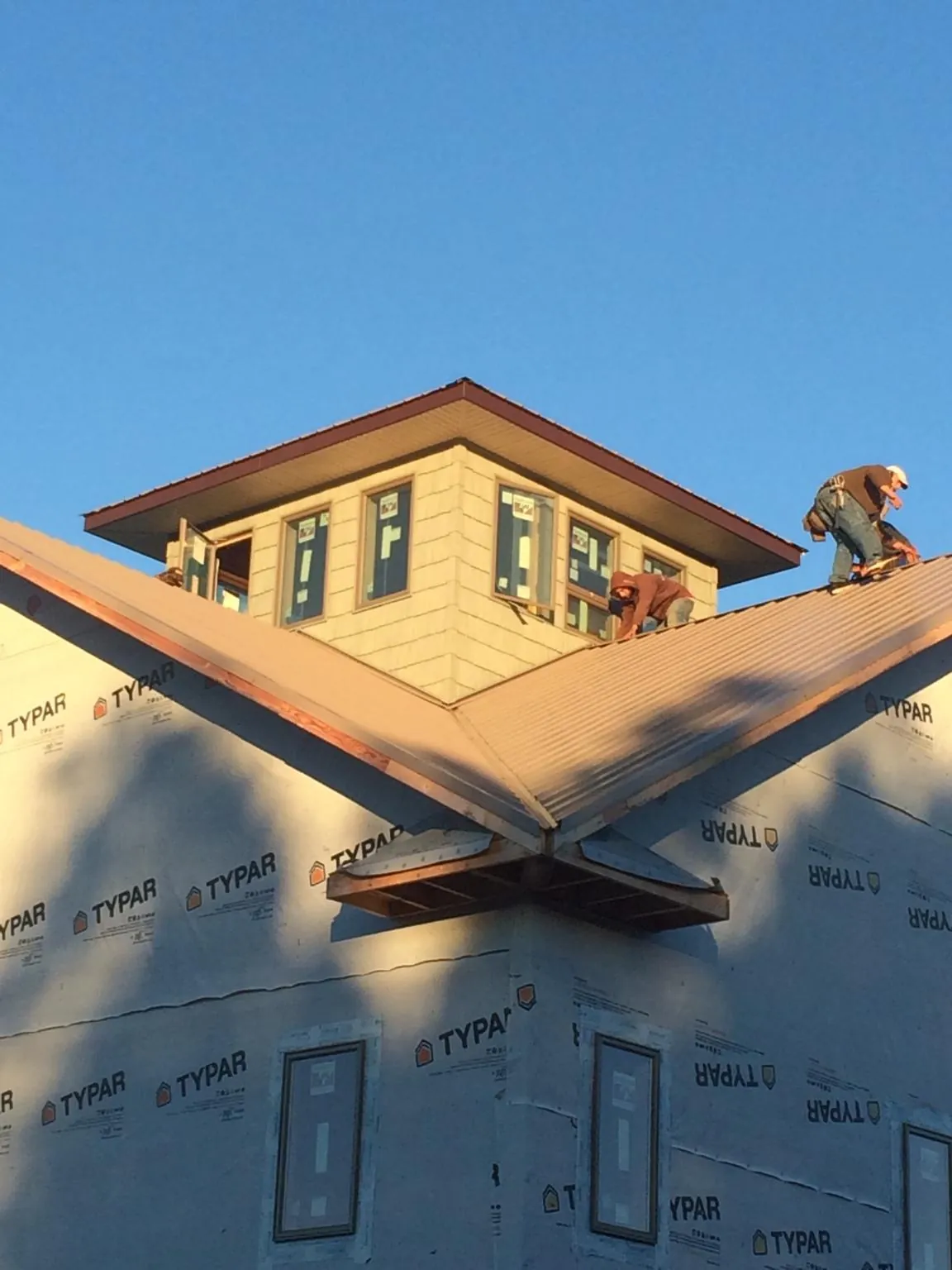 Roofers working around a rooftop cupola on a new metal roof at sunset — Roof Waterproofing in Mcadoo by Roofing Brothers